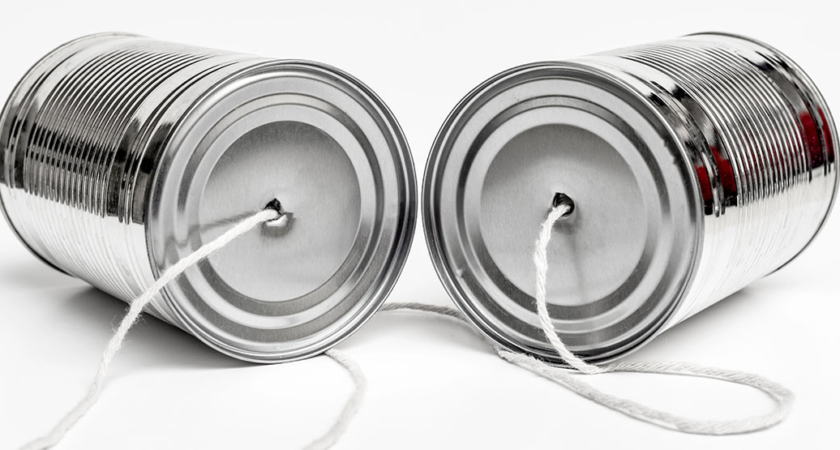 A picture of two cans with string connecting them into a tin can phone