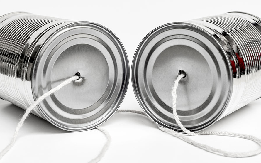 A picture of two cans with string connecting them into a tin can phone